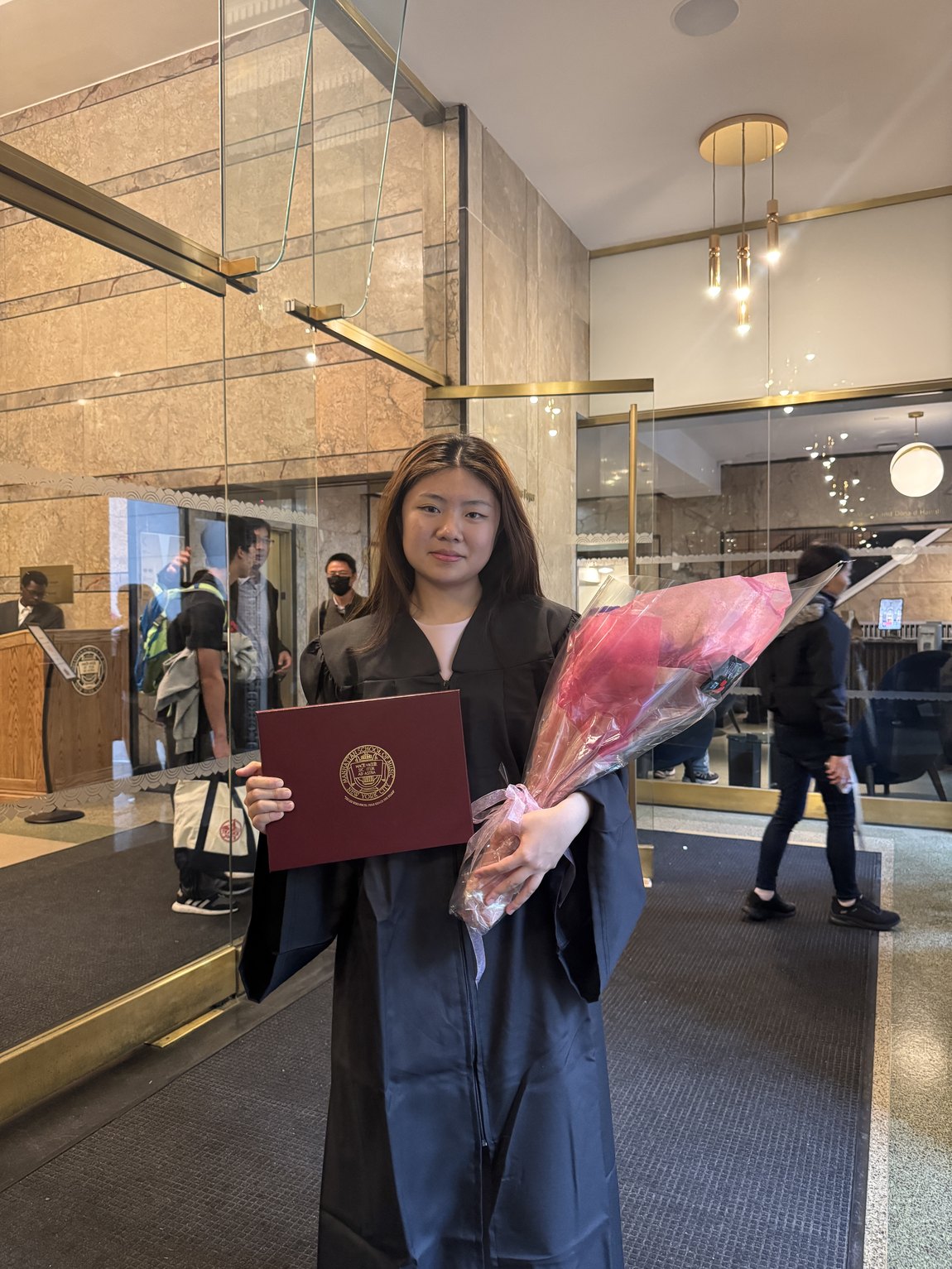 Claire Jiang in cap and gown holding her Manhattan School of Music diploma
